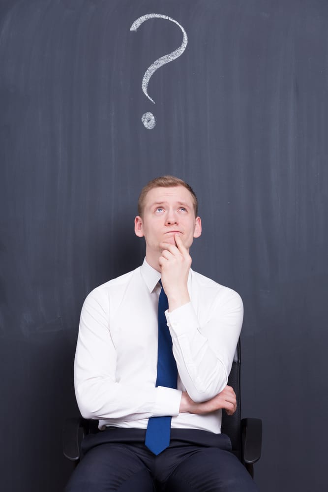 A young man seated, deep in thought with a chalk drawing of a question mark above his head